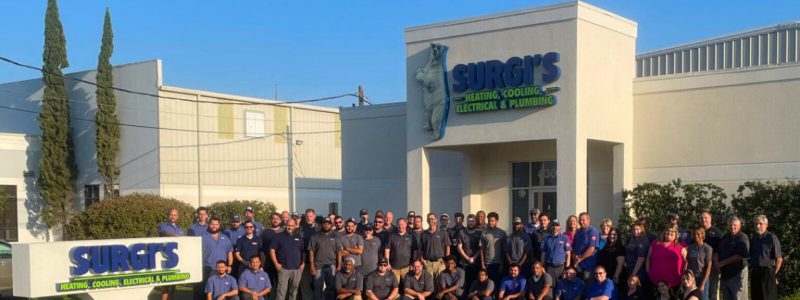 Large group of SURGIS heating, cooling, electrical and plumbing employees posing together outside their New Orleans service location building.