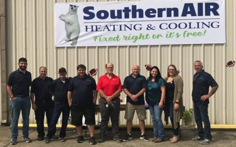 Team of HVAC professionals standing in front of Southern Air Heating & Cooling building with company logo and mascot visible.