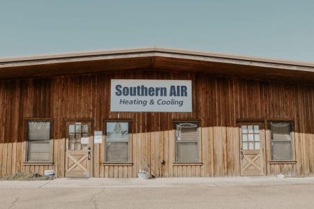 Southern AIR Heating & Cooling storefront with wooden exterior and beige lower panels, featuring multiple windows and doors along the facade.