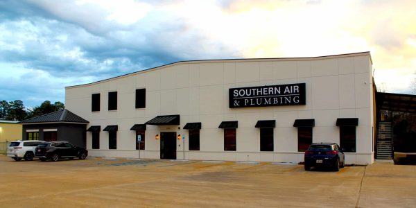 Modern commercial building with cream and black exterior displaying Southern Air & Plumbing signage, multiple service bays, and parked vehicles.